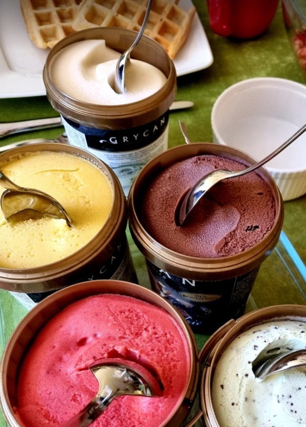lody różnych smaków i kolorów z łyżeczkami w środku