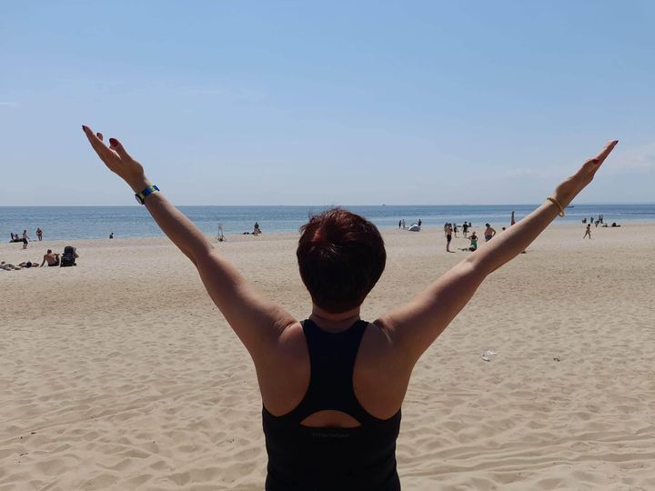 karina sęp z rozłożonymi rękami ku niebu na plaży